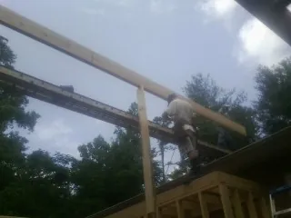Carpenter setting a ridge beam over a new addition frame — Ice Dam Removal by Roofing Brothers in Kindred