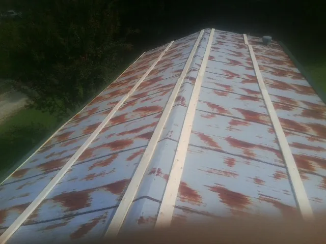Rusted metal roof panels with new wood purlins before replacement — Storm Damage Roof Repair in Kindred by Roofing Brothers