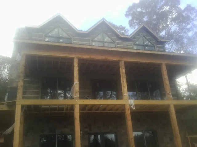 Dormers and porch framing on a large log home under construction — Roof Coating work by our crew in Kindred