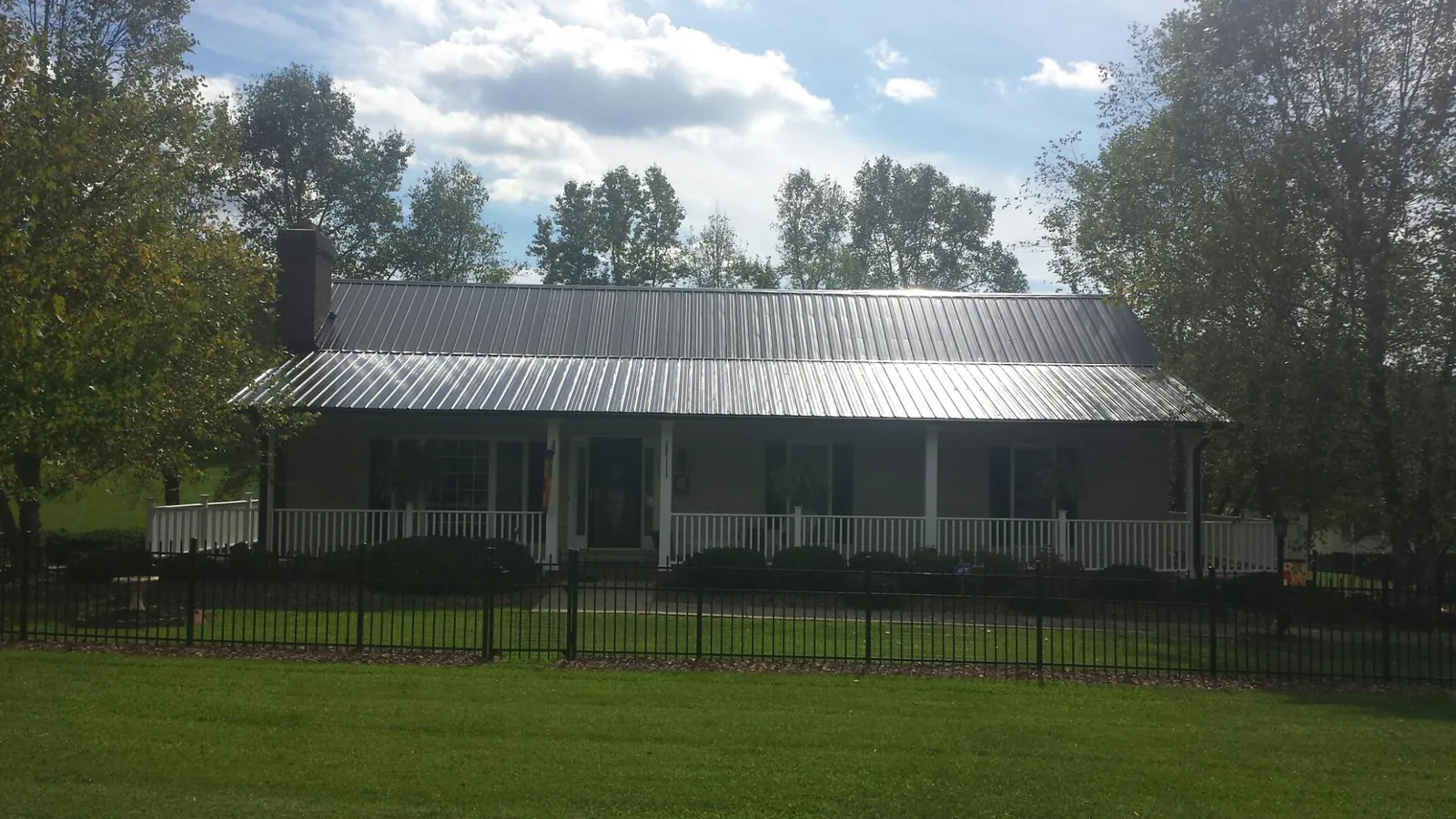 Gray metal roof on a brick ranch with a full width front porch — Gutter Guard Installation work by our crew in Kindred