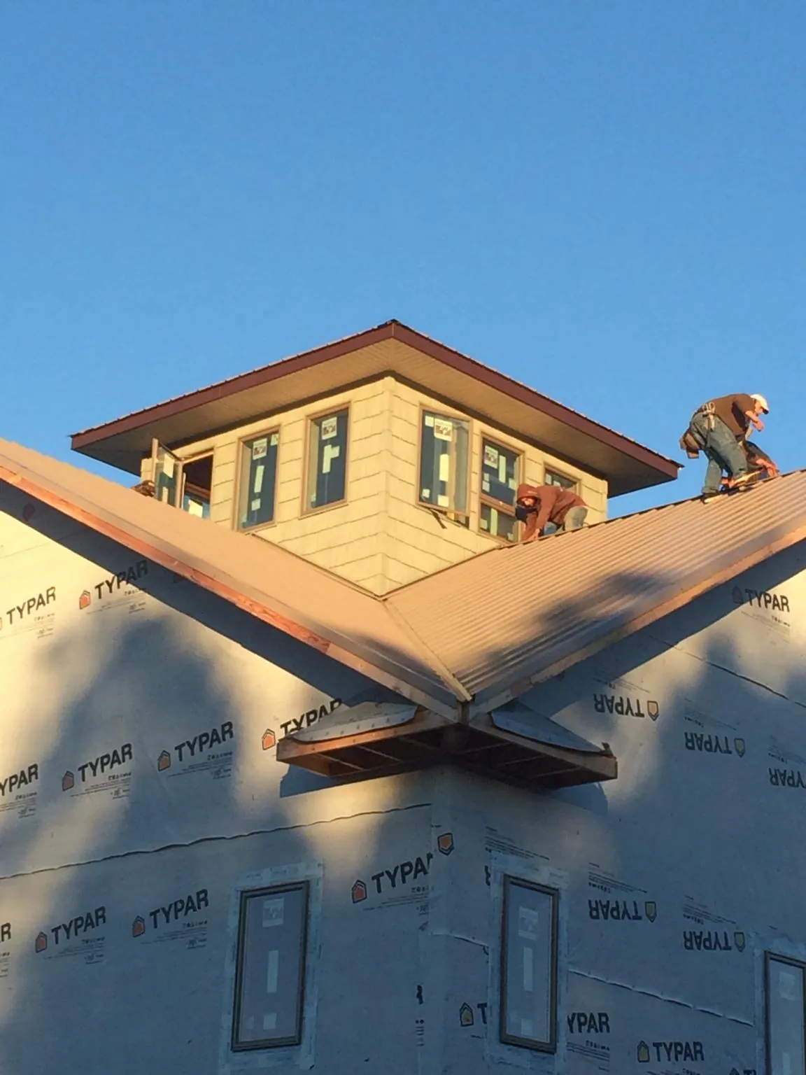 Roofers working around a rooftop cupola on a new metal roof at sunset — Roof Waterproofing in Kindred by Roofing Brothers